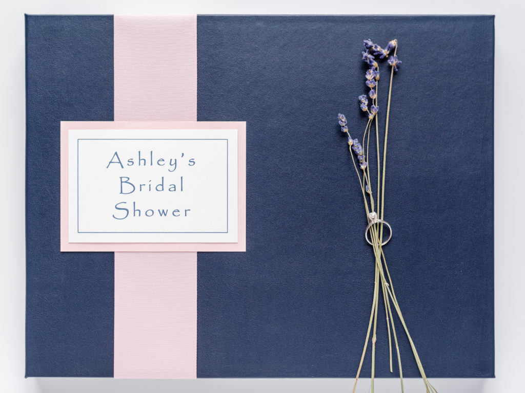 Navy Wedding Shower Guest & Memory Book with pink flat lay ribbon and plaque staged with flowers