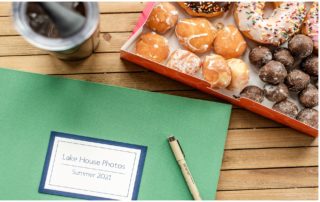 Vacation Home Guest Book green cover next to donuts and coffee on a wooden background