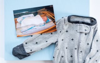blue cloth baby book cover shown with photo of infant and infant pajamas laying on the cover