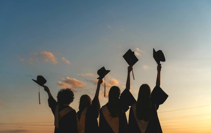 cover photo of students holding up graduation caps at sunset for how to connect with your high school graduate blog post